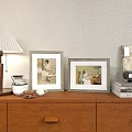 Two Vintage Picture Frames With Portraits On Wooden Dresser With Lamp Mugs And Books