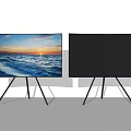 Two TVs Displaying Ocean Sunset Scene On Black Tripod Stands Against White Wall