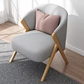 Gray Accent Chair With Wooden Legs And Pink Cushion In Bright Sunlit Room