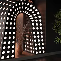 Black Interior Partition With Circular Holes Arched Opening Decorative Branches And Green Plant