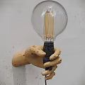 Hand Shaped Wooden Wall Lamp With Transparent Glass Bulb And Filament On White Wall
