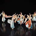 Women In Traditional Costumes Dancing With Flowing Sleeves Skirts On Black Background With Floor Reflections
