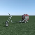 Mobile Agricultural Irrigation Equipment With Red Reel And Wheels On Green Field