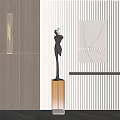Black Carved Sculpture with Orange Base in Modern Interior Featuring Wall Lamp and Artwork