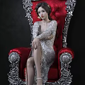 Elegant Woman In Silver Dress Sitting On Red Ornate Chair With Carved Silver Details
