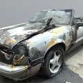 Burnt Convertible Car With Damaged Front End And Rust On Road Surface