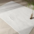White Square Rug With Wavy Texture On Wooden Floor Beside Green Plant Vase