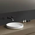 Round White Stone Washbasin with Black Faucet and Toiletries on Dark Bathroom Countertop