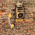 Classic Vintage Yellow Public Telephone Mounted on Red Brick Wall