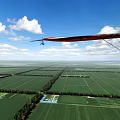 Gyrocopter And Small Airplane Flying Over Green Farmland Under Blue Sky With White Clouds