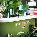 Fresh Greenery Decorated Modern Exhibition Booth Design For Cosmetic Brand Product Trade Show