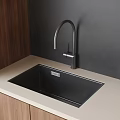 Black Kitchen Sink With Silver Faucet On Light Colored Countertop And Wooden Cabinets
