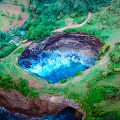 Natural Scenic Giant Blue Lagoon Surrounded by Lush Green Vegetation and Cliffside Grassland Path