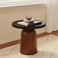 Round Side Table With Black Top Brown Wooden Base Holding Silver Coffee Cup And Book