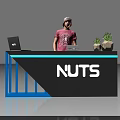 Exhibition Reception Desk Featuring NUTS Logo Blue Frame Gray Countertop Laptop And Potted Plants