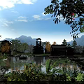 Scenic Water Fountain in Resort Area with Mountain Backdrop Lotus Leaves Reflections and Traditional Buildings