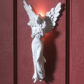 White Angel Statue Wall Lamp With Illuminated Wings On Red Wall