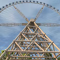 Amusement Park Ferris Wheel With Metal Structure And Blue Cabins Against Blue Sky
