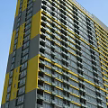 Modern High Rise Building with Yellow Gray Facade and Hinged Doors on Balconies