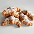 Freshly Baked Golden Flaky Croissants Stacked On White Background With Powdered Sugar