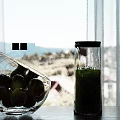 Transparent Glass Bowl With Yellow Fruits And Glass Jug Of Green Liquid On Wooden Tabletop