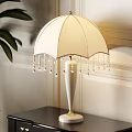White Decorative Table Lamp With Umbrella Shaped Lampshade Beaded Fringes And Cylindrical Base With Gold Trim