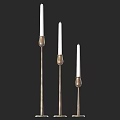 Three Brass Candle Lamps With Slender Stands And White Candles For Home Decor
