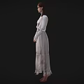 Woman in light colored long dress wearing glasses with hands crossed standing against black background