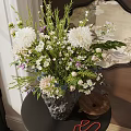 Black Textured Vase With White Purple Flowers On Dark Table Near Round Decorative Mirror