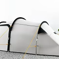 White Tent Featuring Black Curved Structure Yellow Ropes Securing On Gravel Ground Near Green Trees
