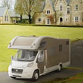 Luxury Motorhome Parked On Driveway Near Large House With Green Lawn