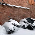 Urban Buildings With Red Brick Walls Snow Covered Black Plastic Bags on Ground