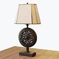 Black Carved Round Base Table Lamp With Beige Fabric Shade On Wooden Table