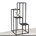 Modern Black Metal Shelving Unit With Multi Tier Varying Height Shelves And Small Potted Plant