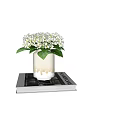 White Hydrangea Flowers In Ceramic Vase With Drip Design On Stacked Books