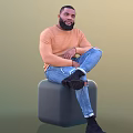 Man Sitting On Grey Cube Stool Wearing Orange Sweater Blue Ripped Jeans And Black Shoes
