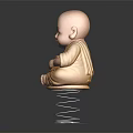 Little Monk Statue In Yellow Robe Sitting Cross Legged On Spring Base