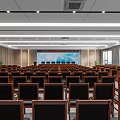 Spacious Conference Room With Rows Of Black Chairs Large Screen Ceiling Lights And Windows