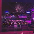 Hard Rock Bar Interior With Purple Lighting Music Neon Sign And Stage Seating Area