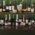 Elegant Wine Bottles And Glasses Collection On Countertop With Green Tiled Wall And Drawers
