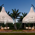 White Woven Outdoor Tents Surrounded By Palm Trees With Seating Areas