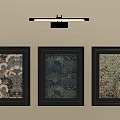 Three Framed Artworks On Beige Wall With Above Wall Light Fixture