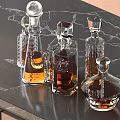 Elegant Crystal Liquor Bottles and Glasses with Various Colored Liquids on Black Marble Tabletop