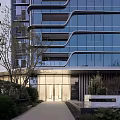 Modern High Rise Building Facade With Glass Curtain Wall Curved Design And Greenery Around Entrance