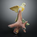 Ceramic Yellow Bird Figurine Perched On Textured Tree Branch With Green Leaves