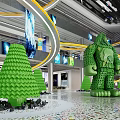 Shopping Mall Lobby With Green Tree Humanoid Sculptures Curved Yellow Lines Screens And Colorful Floor