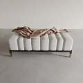 Soft Upholstered Ottoman with Light Gray Tufted Surface and Metallic Legs with Draped Scarf