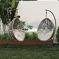 Two Rattan Hanging Outdoor Chairs With White Cushions Curved Metal Stand In Garden Lawn