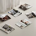 Open Magazines Scattered on White Surface with Pages Showing Images Text and White Curtain
