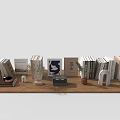 Various Colored Books On Wooden Table With Decor Items Including Dried Flowers Small Ornaments
